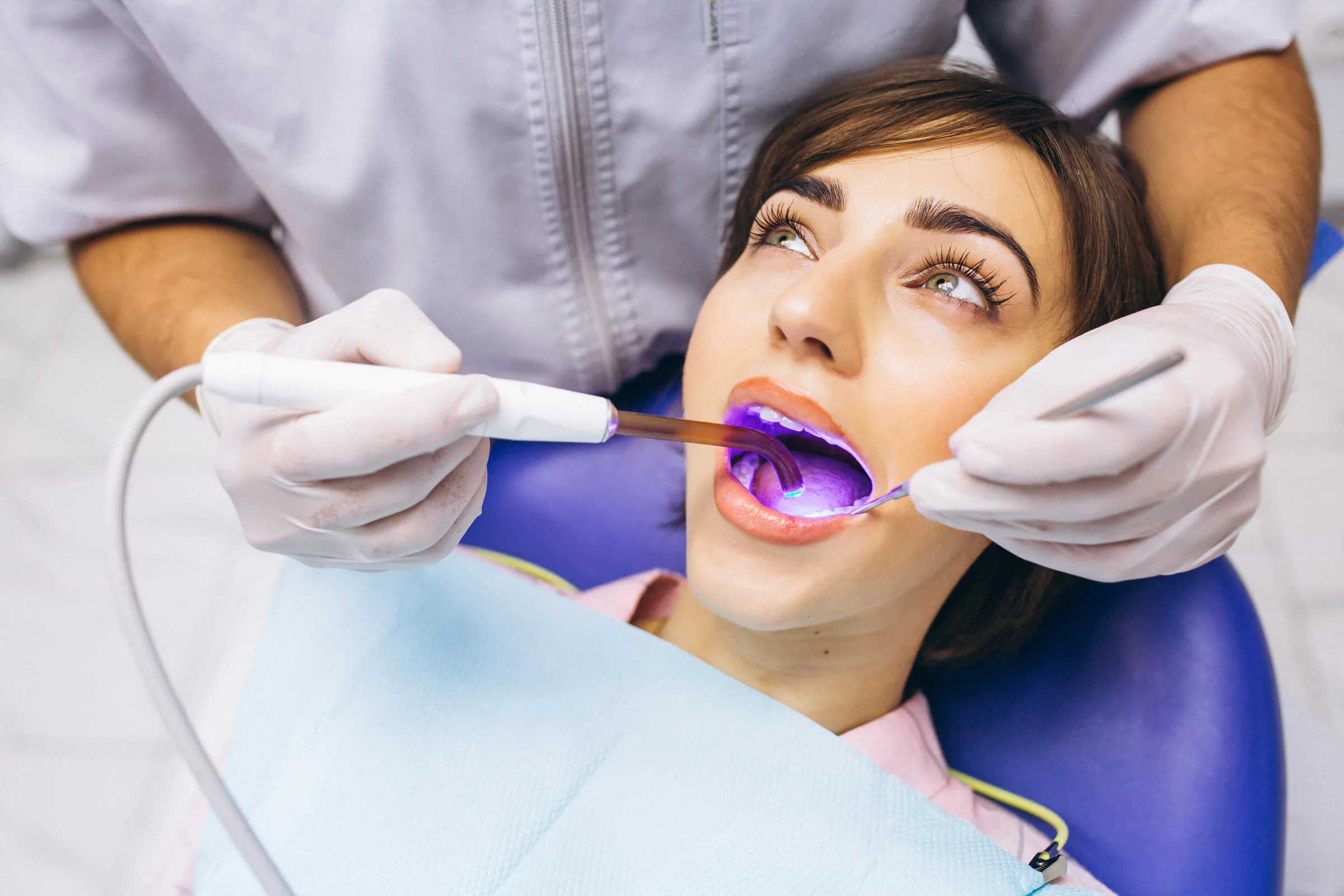 Dentist examining a smiling patient's teeth in a bright, modern dental clinic